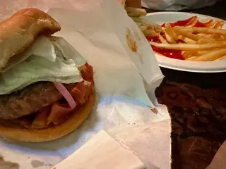 Photo of a burger in paper and fries